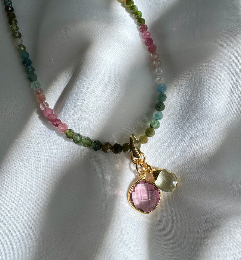 Necklace with multicolored beads and a pink pendant on a white background