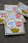 Waffle House coasters with lipstick prints and handwritten notes on a dark surface