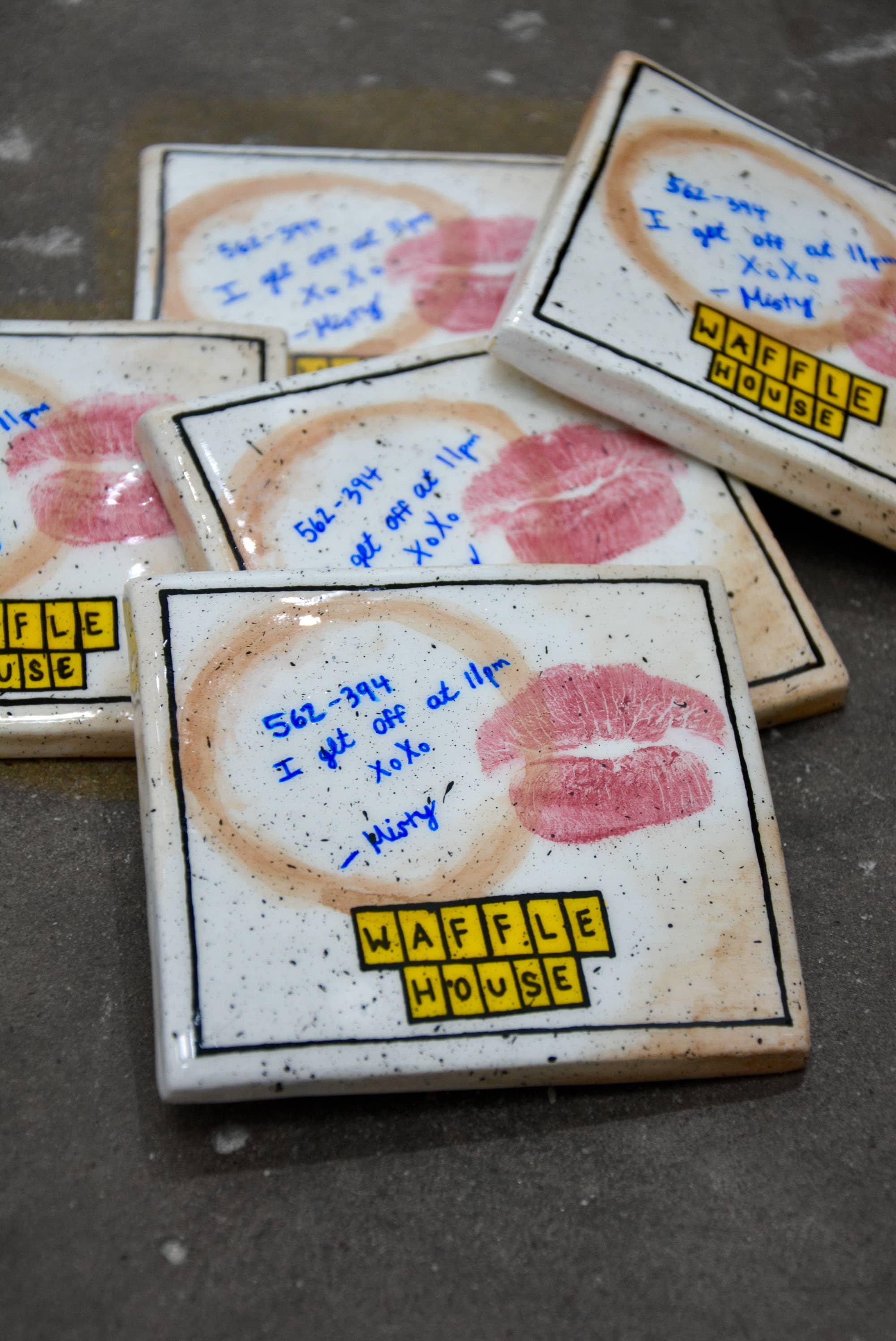 Waffle House coasters with lipstick prints and handwritten notes on a dark surface