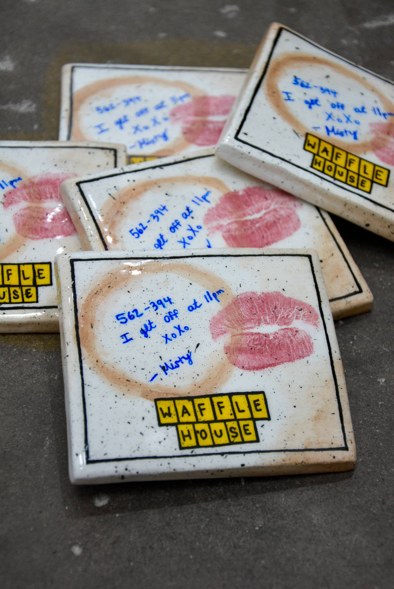 Waffle House coasters with lipstick prints and handwritten notes on a dark surface