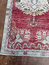 Close-up of a patterned rug with red and white colors on a wooden floor.