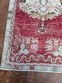 Close-up of a patterned rug with red and white colors on a wooden floor.