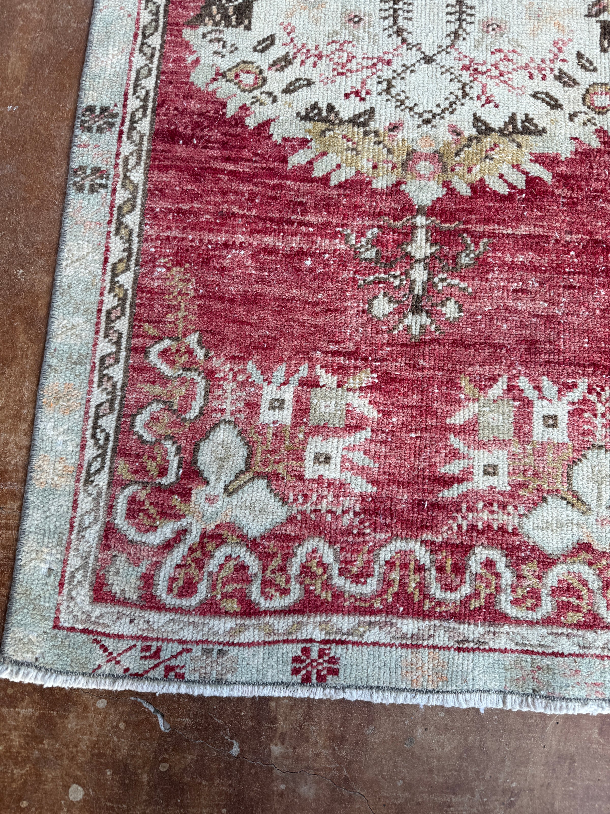 Close-up of a patterned rug with red and white colors on a wooden floor.