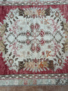 Close-up of a patterned rug with floral designs on a wooden floor.