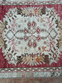 Close-up of a patterned rug with floral designs on a wooden floor.
