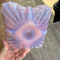 Hand holding a translucent purple and pink object against a wooden surface