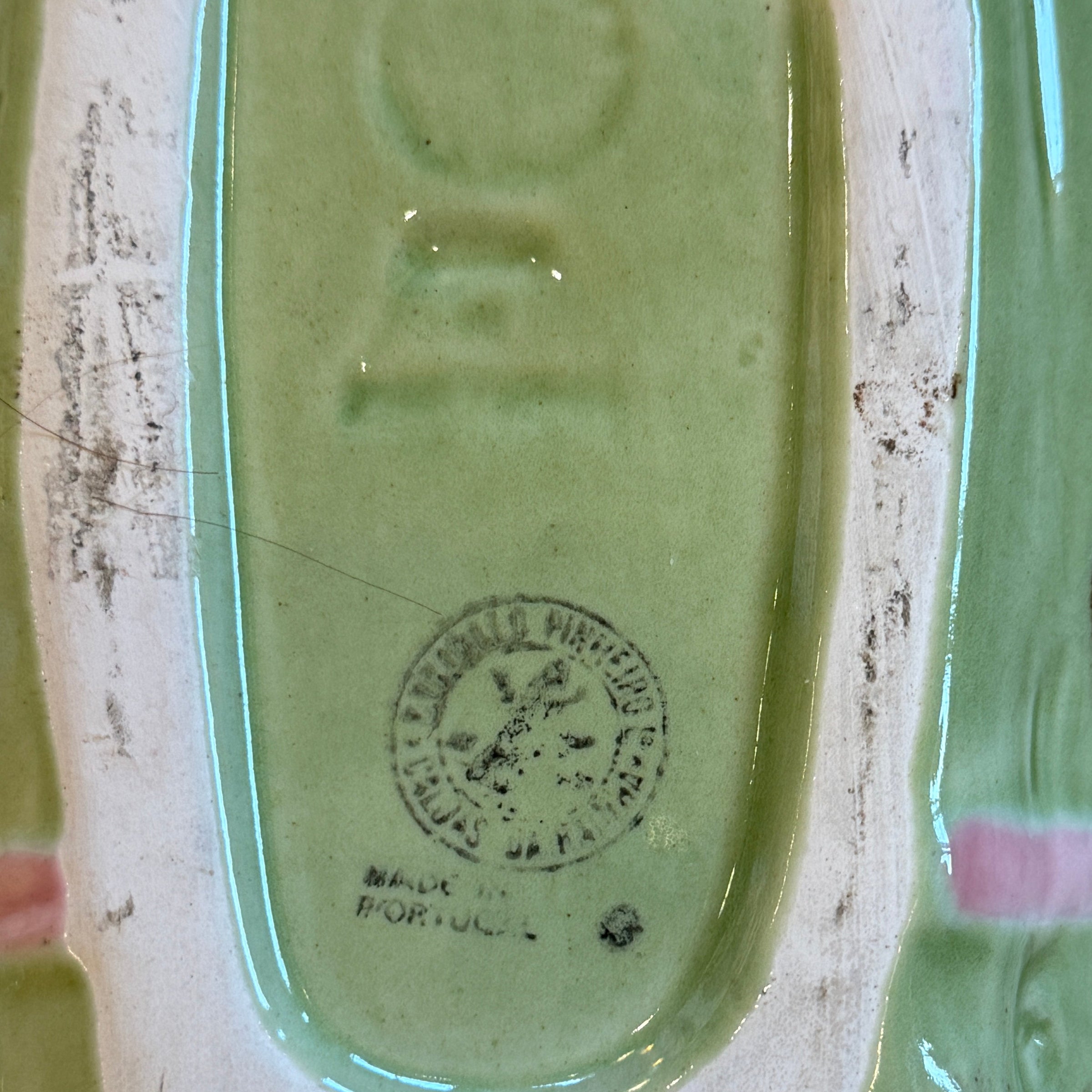 Green ceramic dish with a logo on a textured surface
