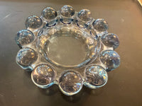 Clear glass dish with spherical embellishments on a dark surface