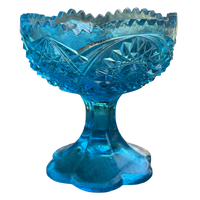 Blue glass footed bowl with intricate cut patterns on a white background