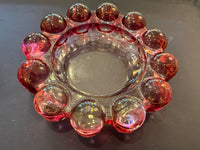 Clear glass candle holder with pink marbles on a dark surface