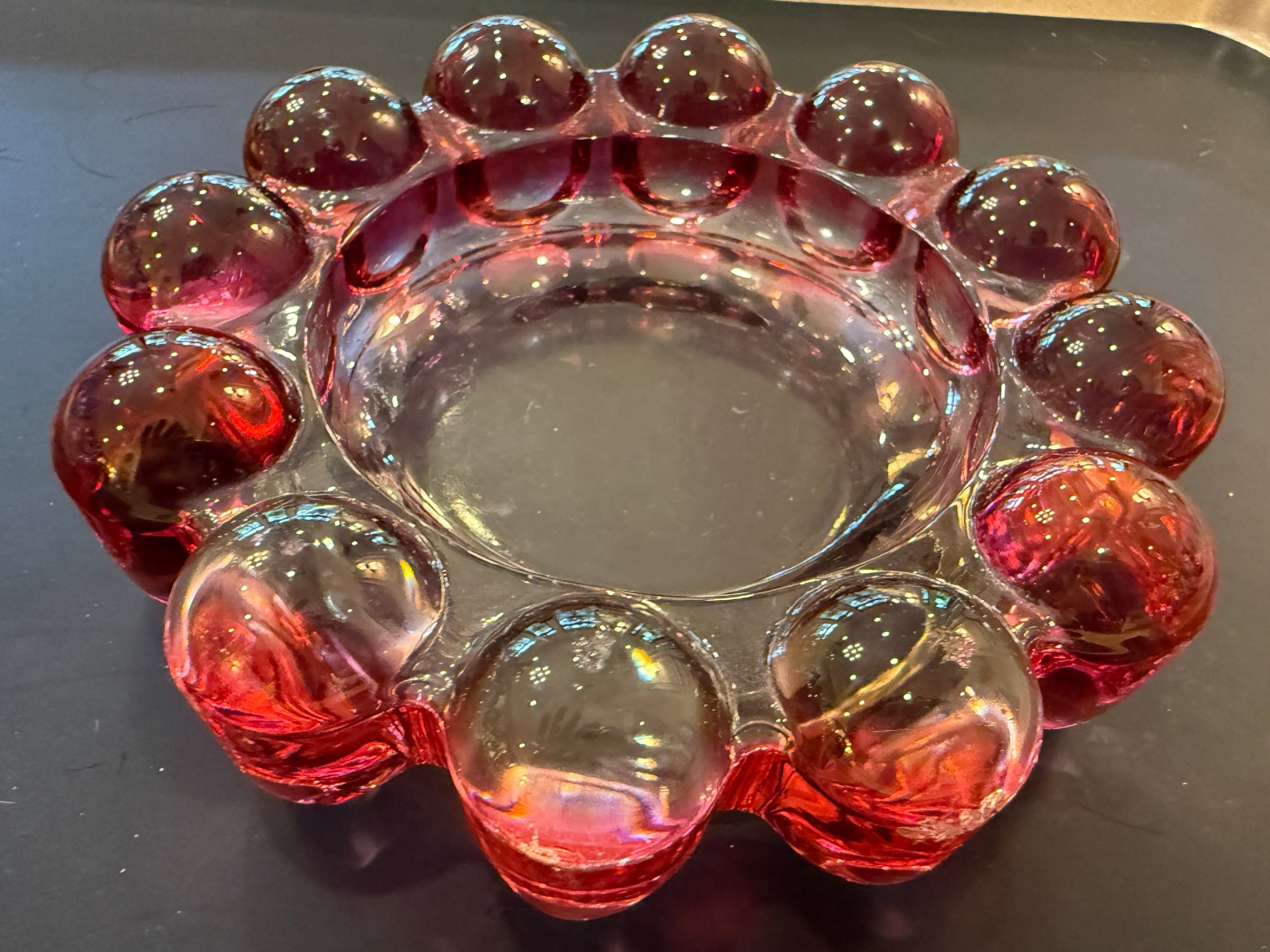 Clear glass candle holder with red-brown decorative elements on a black surface