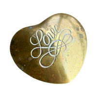 Heart-shaped brass object with 'Love' engraved on a white background