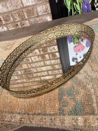 Decorative gold metal tray on a textured surface with a brick wall background