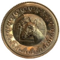 Decorative brass plate with a horse's head in the center on a white background