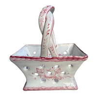 White ceramic basket with pink floral patterns and matching spoon on a white background