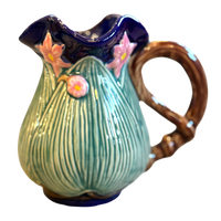 Ceramic pitcher with floral design on a white background