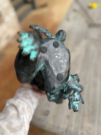 Bronze frog sculpture on a wooden surface