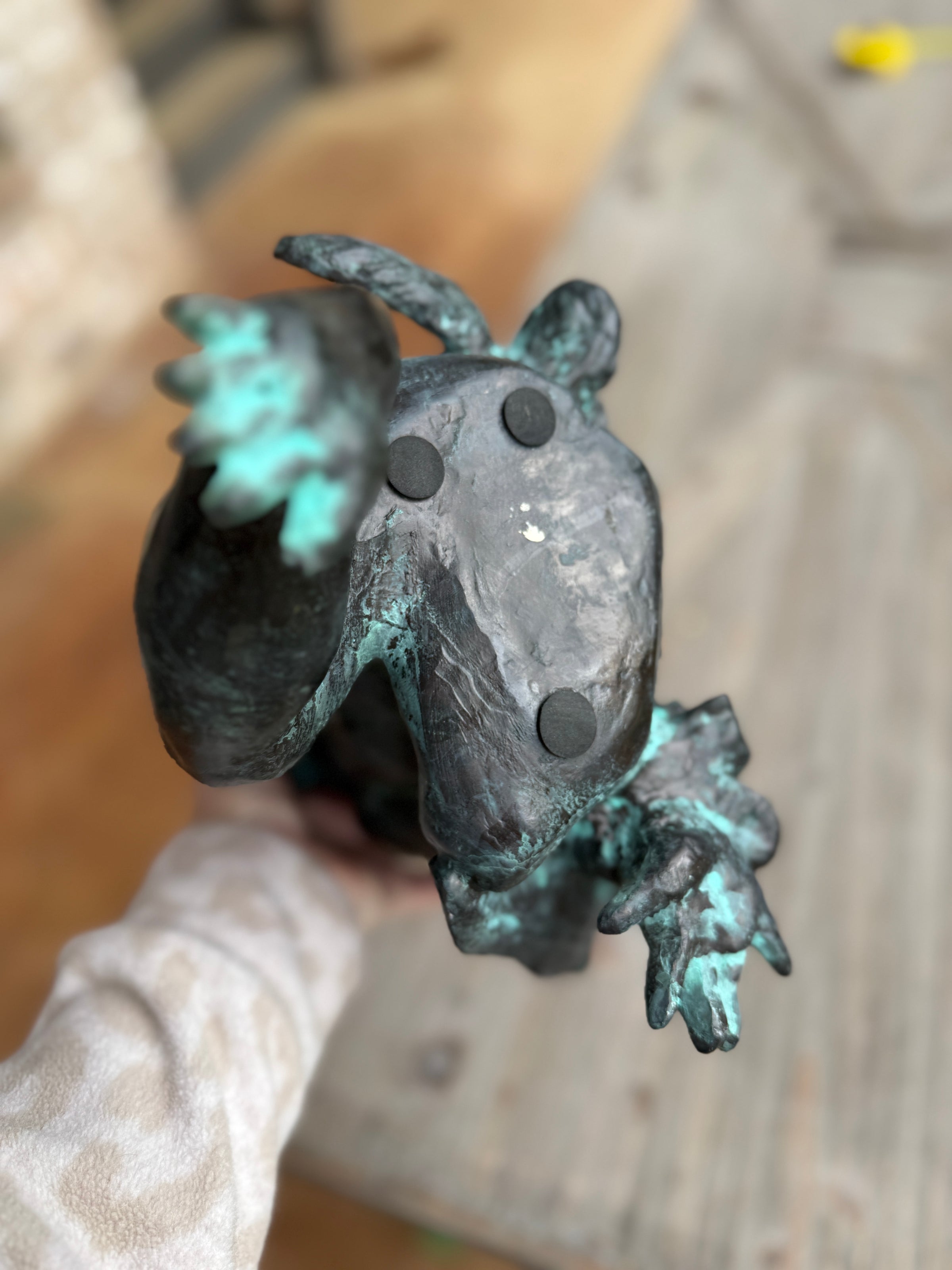 Bronze frog sculpture on a wooden surface