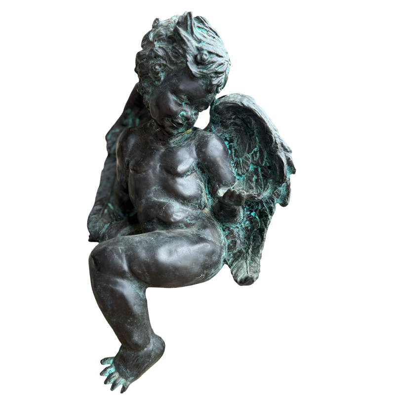 Bronze statue of a winged child on a white background