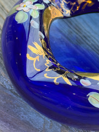 Close-up of a blue ceramic item with gold floral designs on a wooden surface