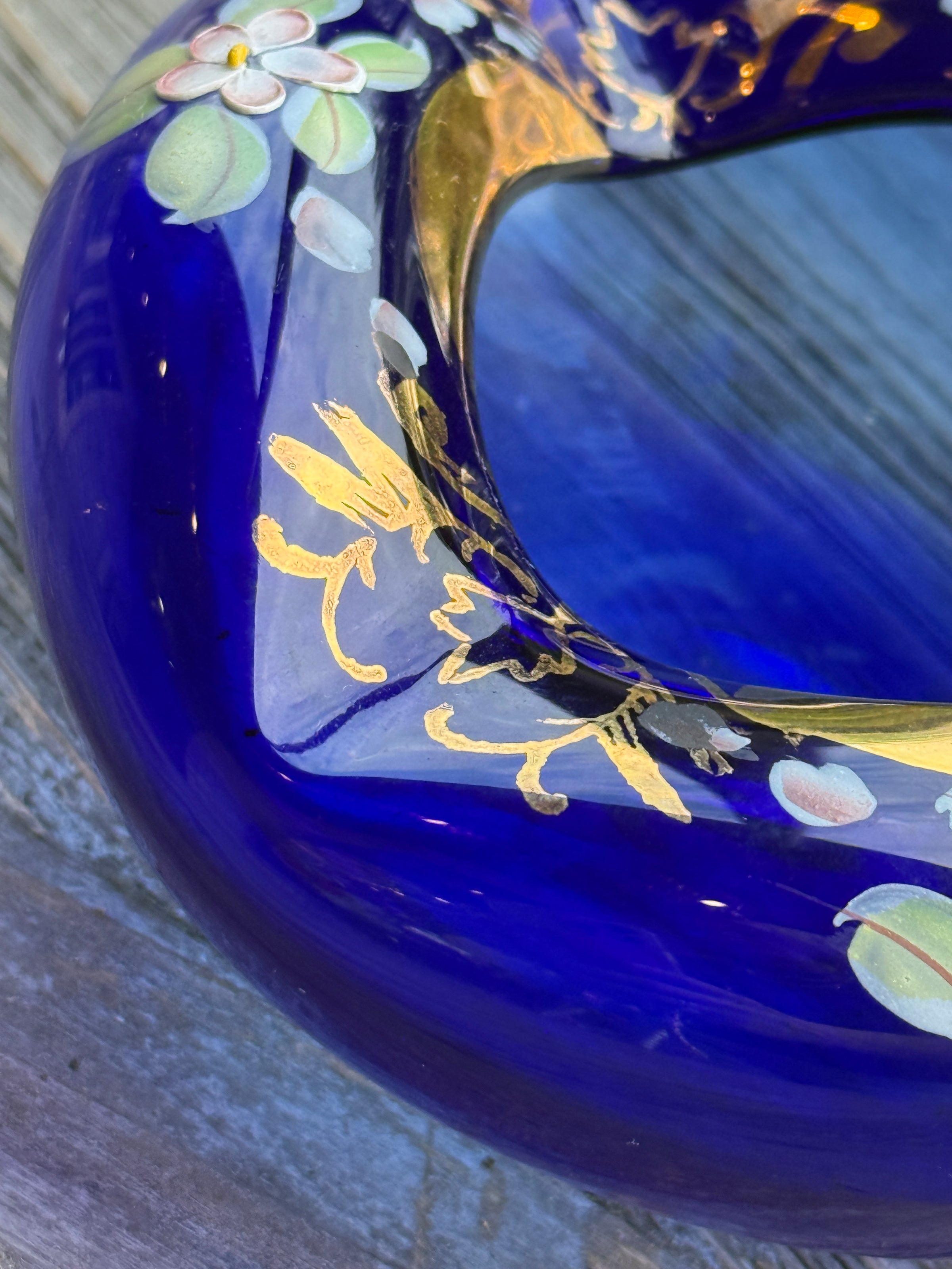 Close-up of a blue ceramic item with gold floral designs on a wooden surface