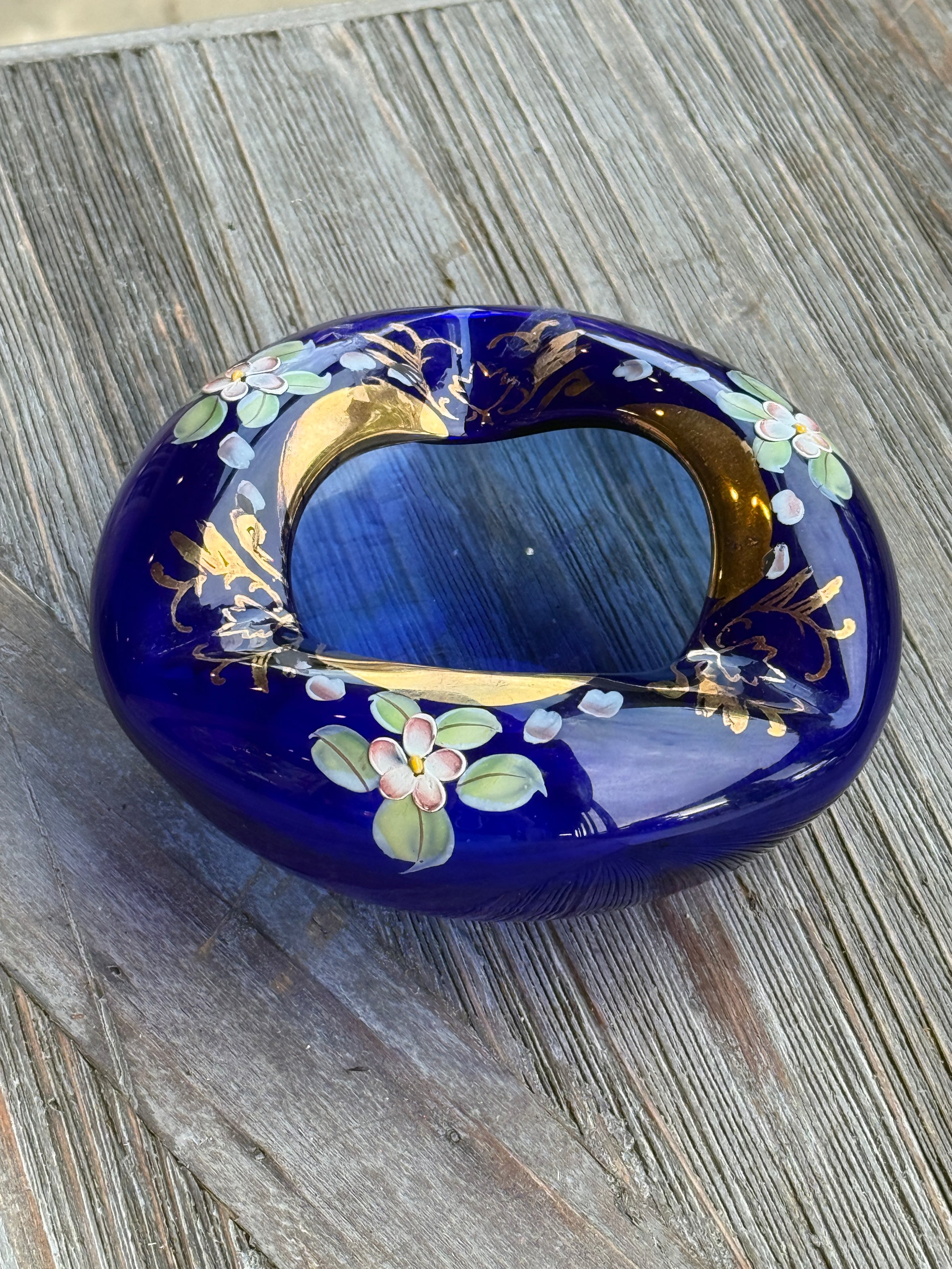 Decorative blue stone with floral and gold designs on a wooden surface