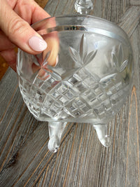 Clear glass pineapple-shaped object held by a hand on a wooden surface