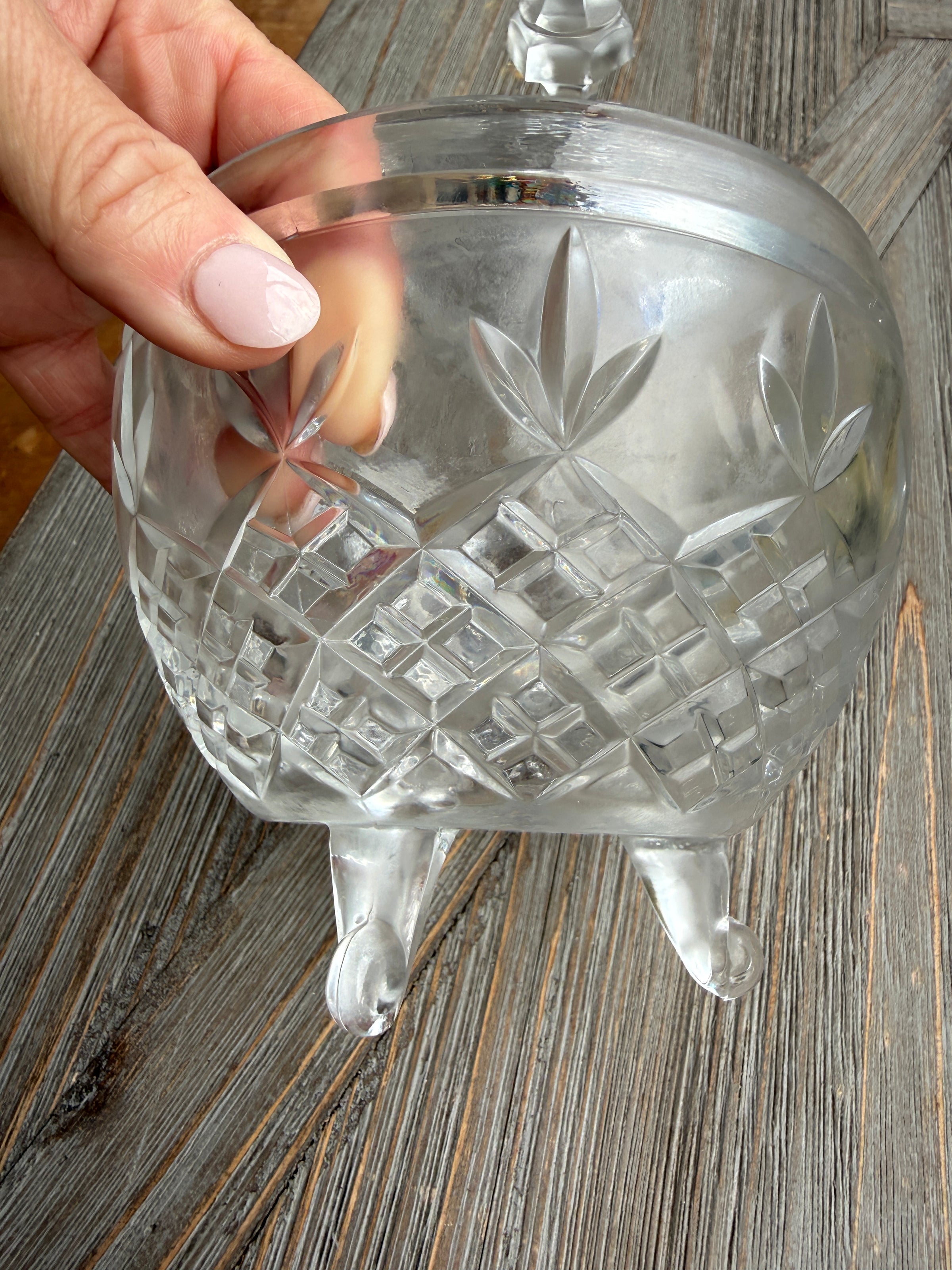 Clear glass pineapple-shaped object held by a hand on a wooden surface