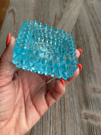 Hand holding a blue textured ball against a wooden background