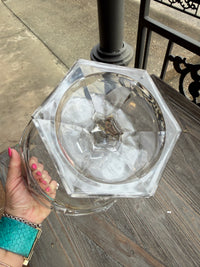 Hexagonal glass with ice cubes held by a hand on a wooden surface
