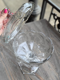 Clear glass pitcher held by a hand on a wooden surface