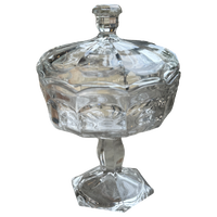 Clear glass candy dish with a lid on a white background