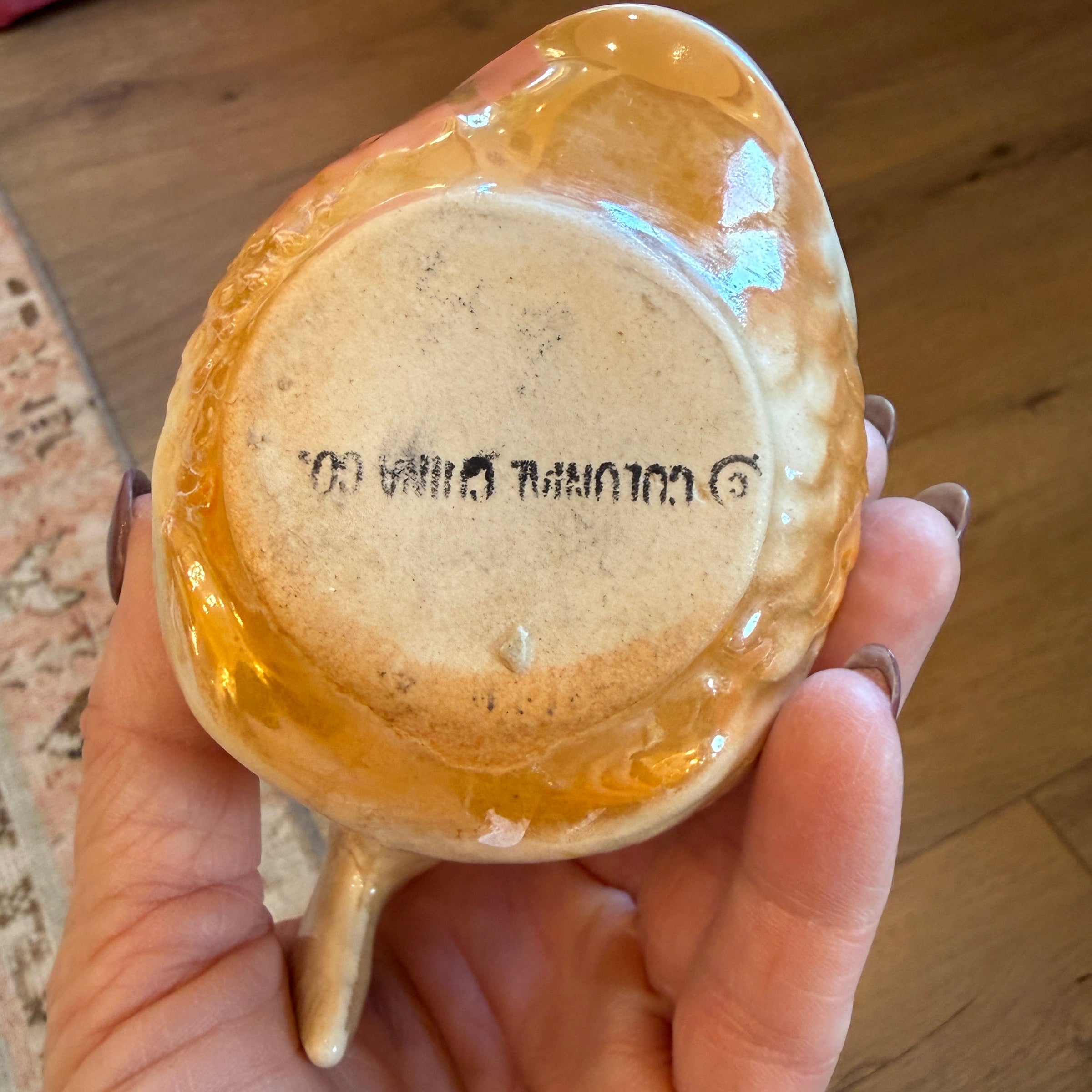 Hand holding a small ceramic cup with a lid, showing a brand logo on the lid.