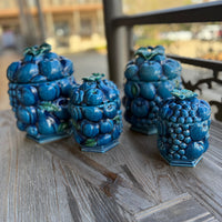 Set of blue ceramic containers with berry design on a wooden surface
