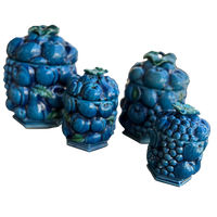 Set of four blue ceramic jars with grape design on a white background