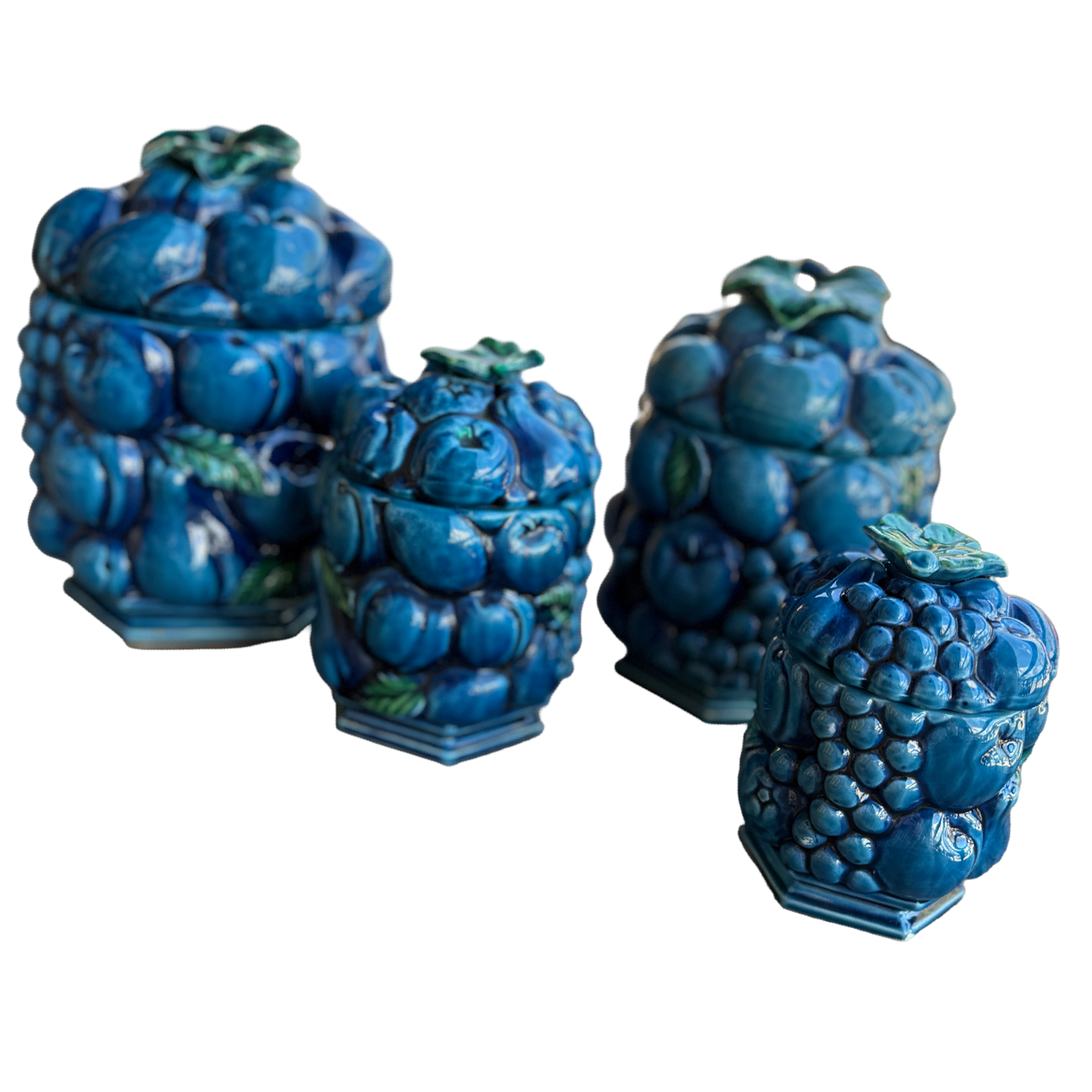 Set of four blue ceramic jars with grape design on a white background