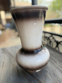 Smoky glass vase on a wooden surface with a blurred outdoor background