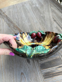Decorative ceramic bowl with colorful design held by a hand on a wooden surface