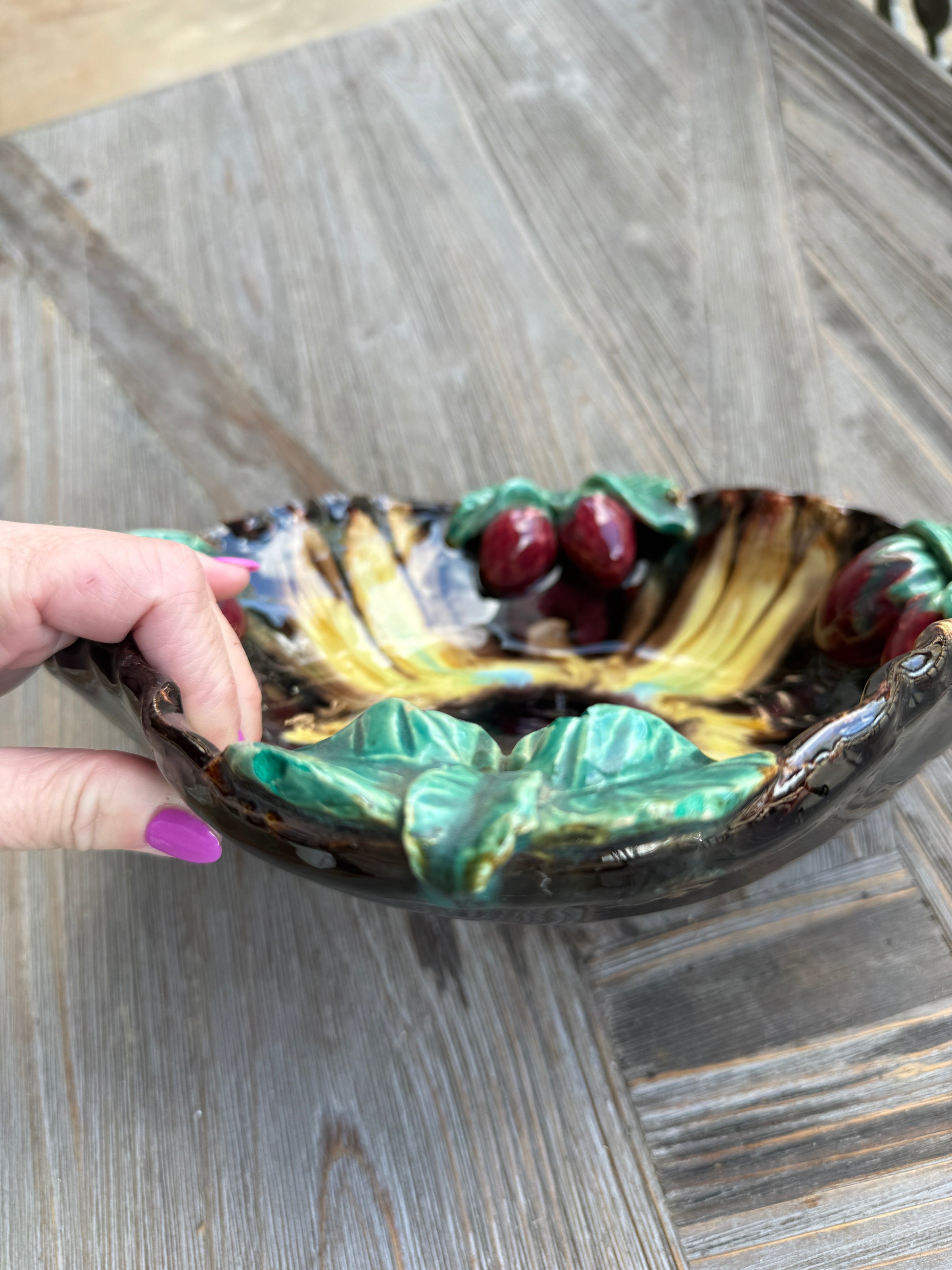 Decorative ceramic bowl with colorful design held by a hand on a wooden surface