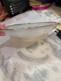 White ceramic plate with gold rim held over a patterned fabric background