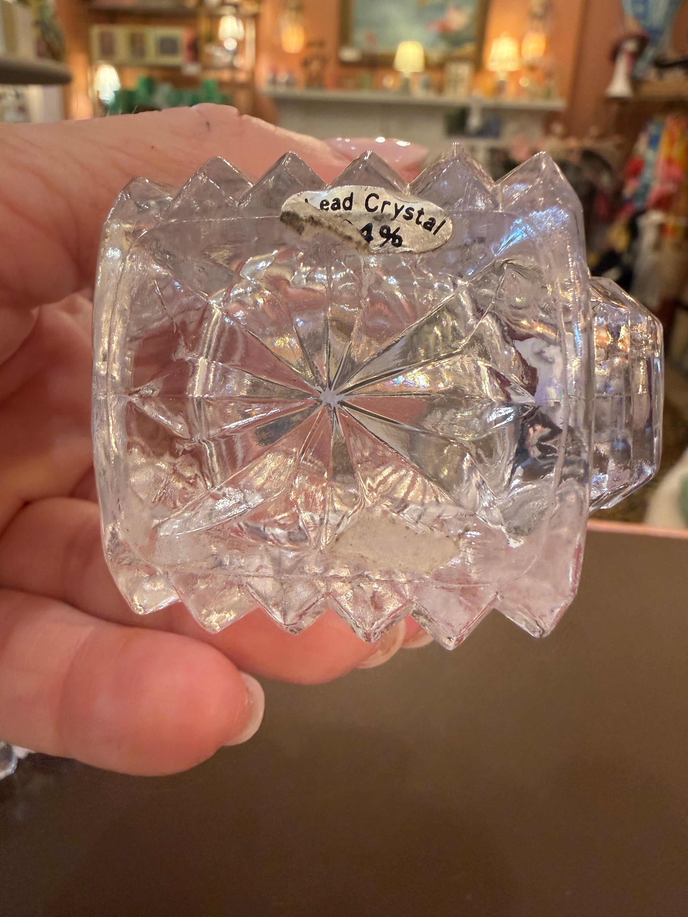 Clear crystal container held in a hand with a blurred background