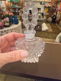 Clear decorative item held by a hand in front of a cluttered background