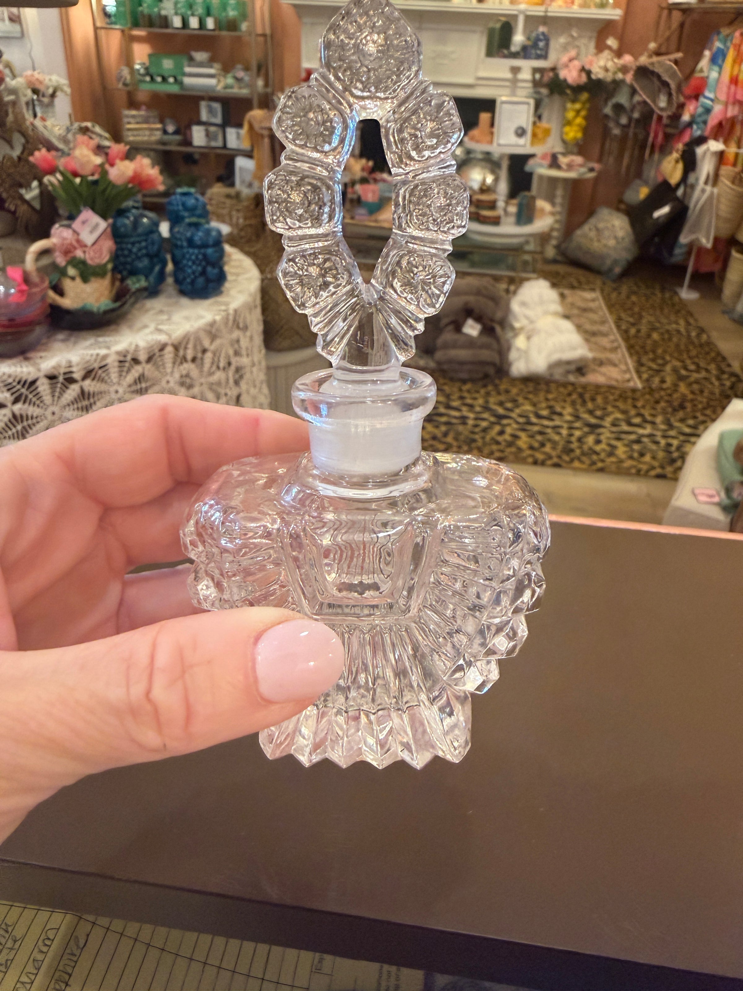 Clear decorative item held by a hand in front of a cluttered background