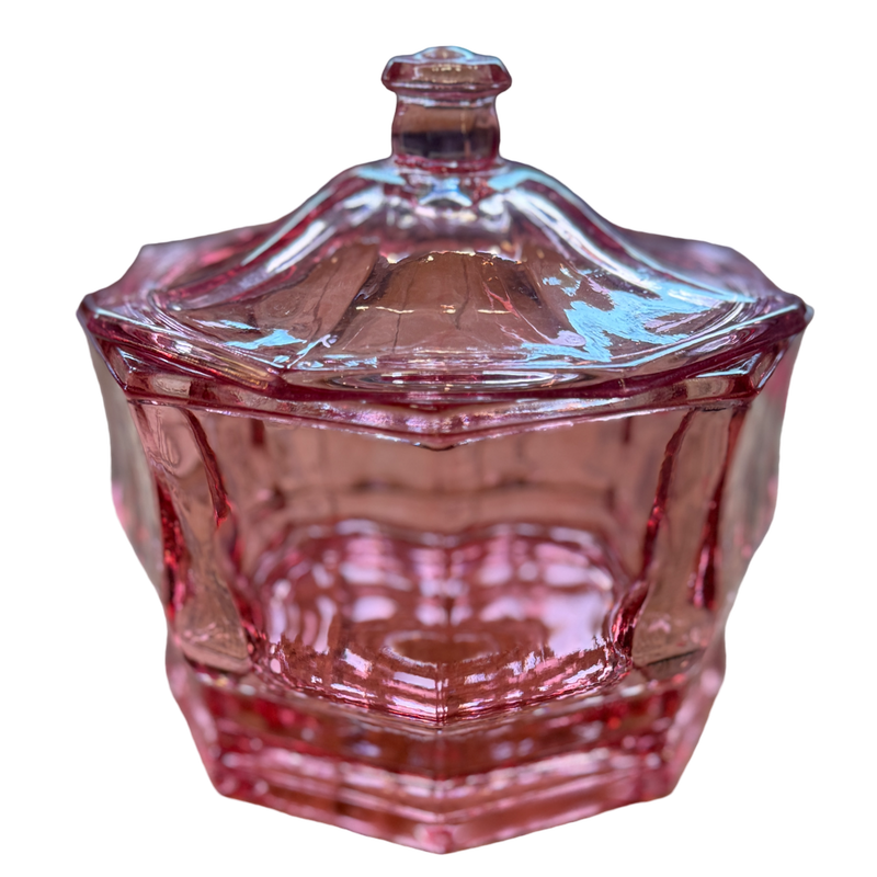Pink glass candy dish with a lid on a white background