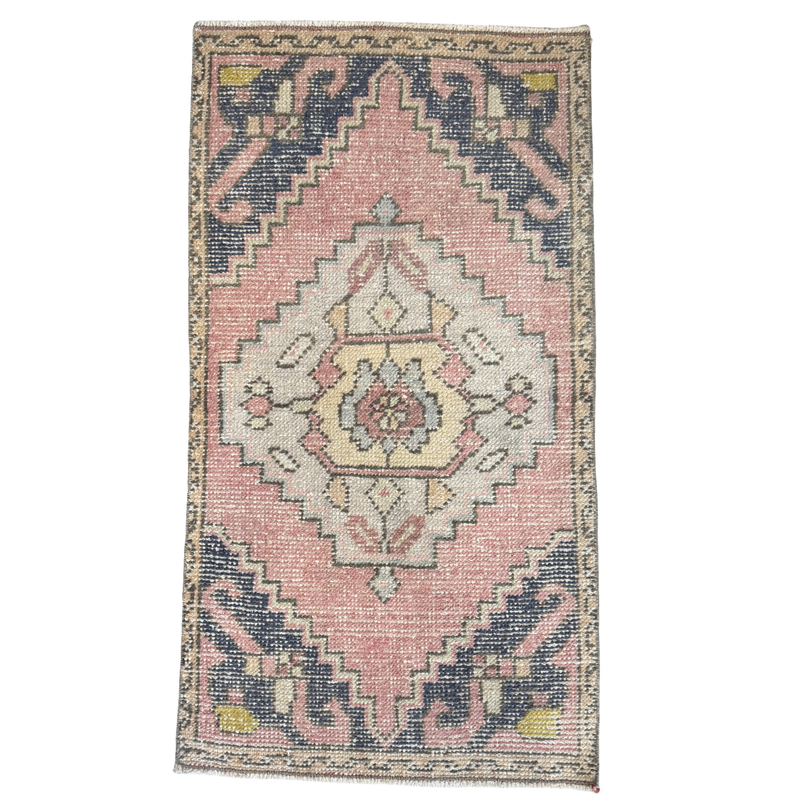 Decorative rug with a pink and blue geometric pattern on a white background