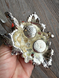 Decorative metal object held by a hand on a wooden surface