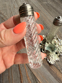 Hand holding a decorative salt and pepper shaker set on a wooden surface