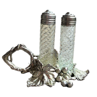 Decorative salt and pepper shakers with a silver holder on a white background