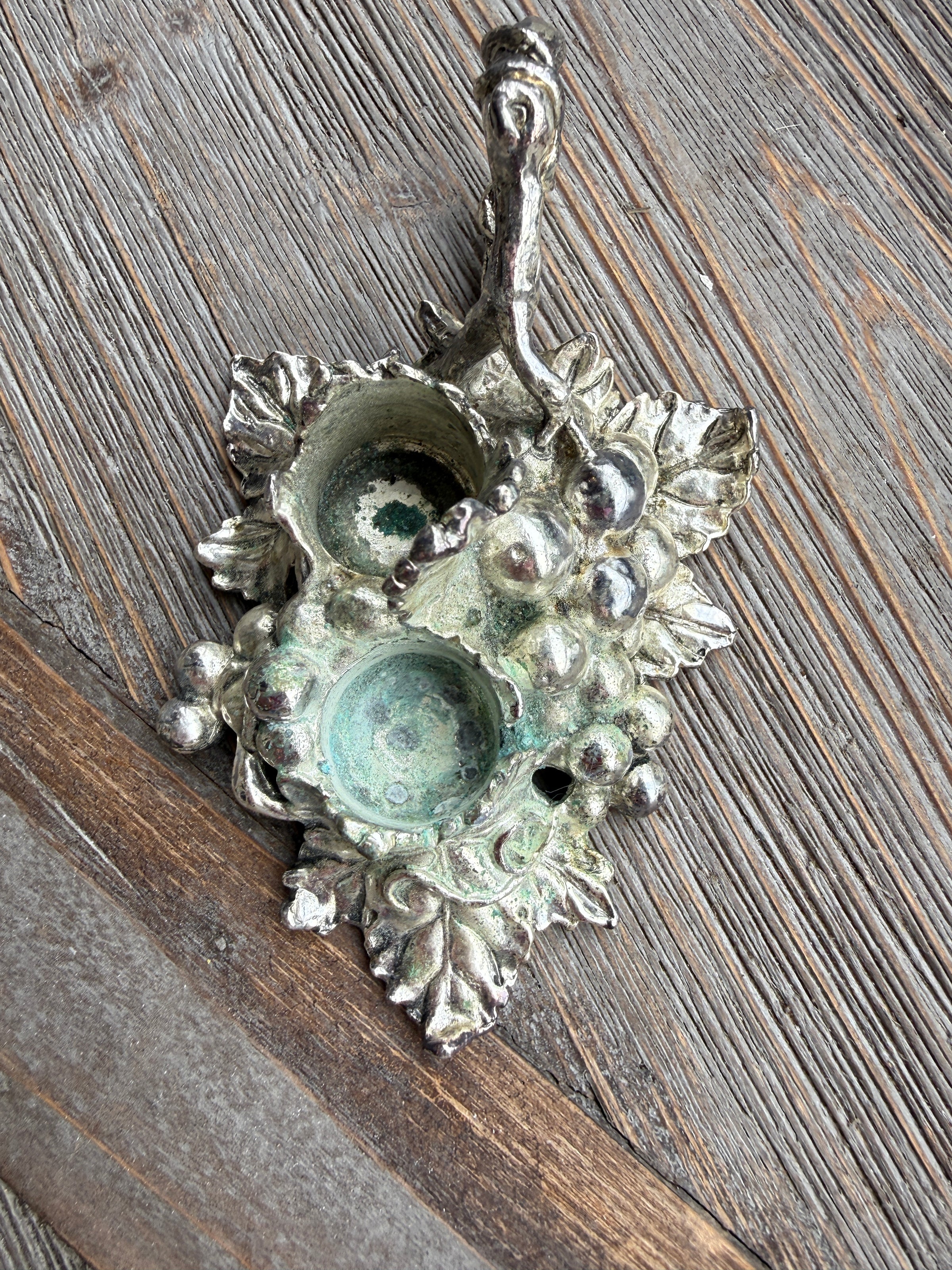 Decorative metal wall hook with floral design on a wooden surface