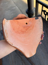 Person holding a terracotta pot with a worn surface
